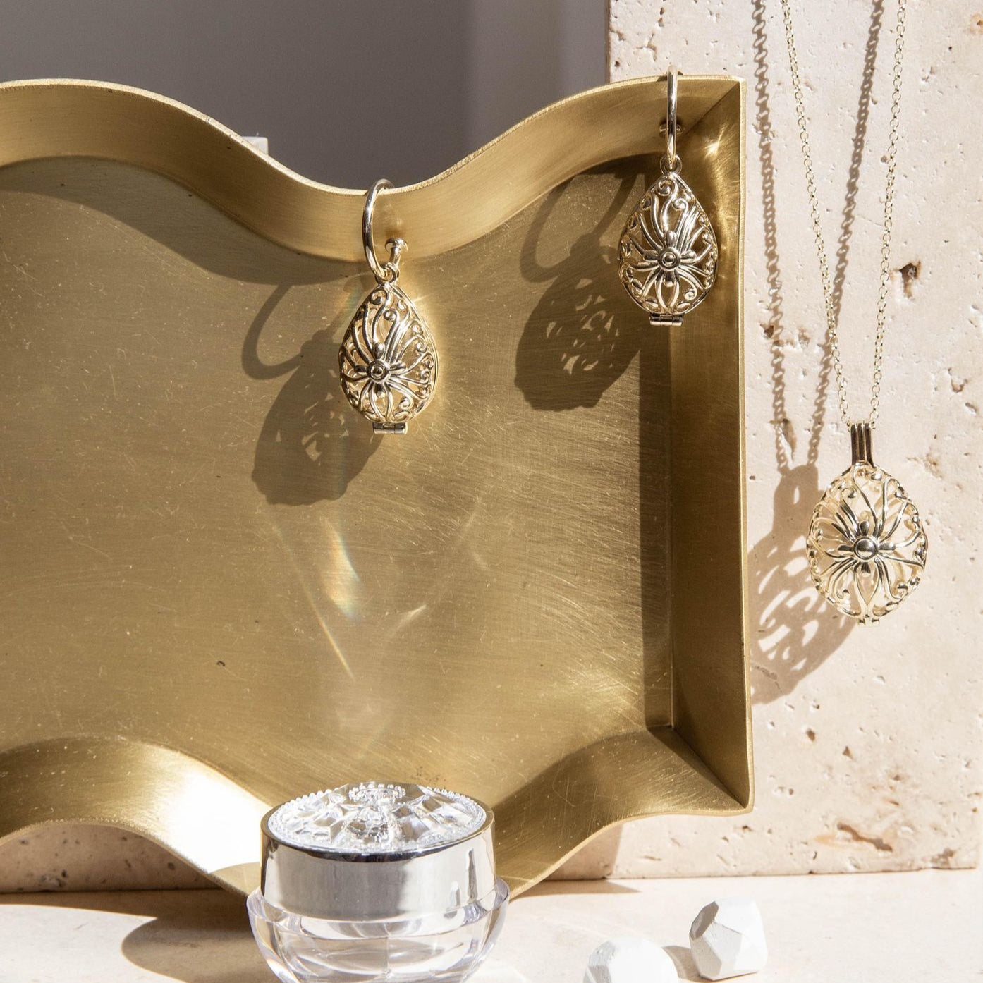 Gold jewelry set with earrings and a necklace on a textured surface